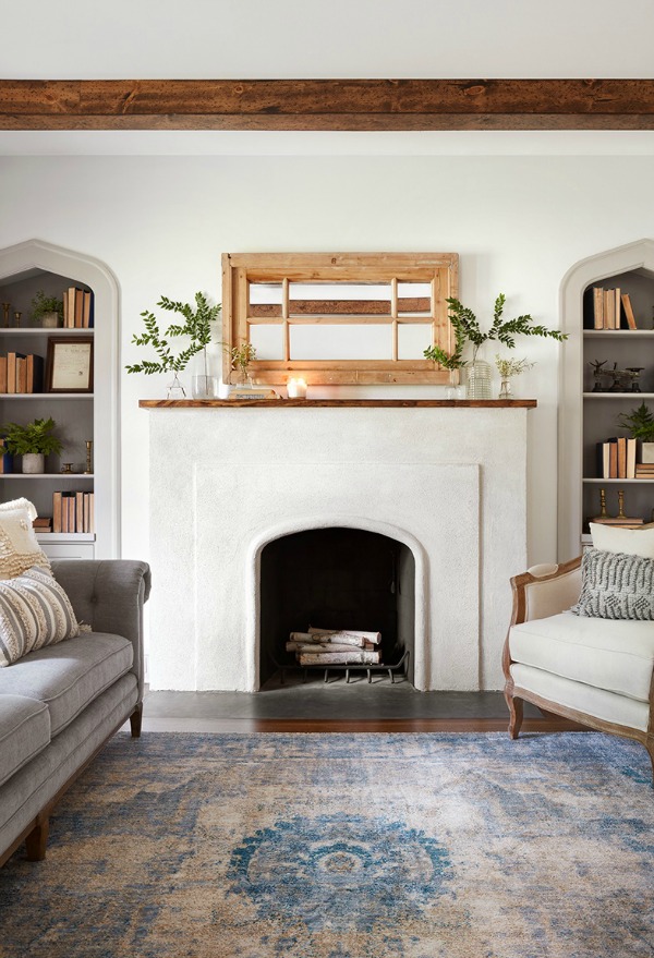 Simple fireplace in cottage living room.  Come get inspired by Tranquil and Timeless Tudor Design Details From a Serene 1920s Texas Cottage renovated on HGTV's Fixer Upper by Chip and Joanna and known as the Scrivano House. #fixerupper #scrivano #cottagestyle #interiordesign #greytrim #serenedecor #fireplace #livingroom #cottagedesign