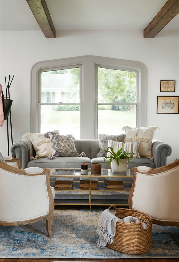 Serene living room with soft greys and white.  Come get inspired by Tranquil and Timeless Tudor Design Details From a Serene 1920s Texas Cottage renovated on HGTV's Fixer Upper by Chip and Joanna and known as the Scrivano House. #fixerupper #scrivano #cottagestyle #interiordesign #greytrim #serenedecor #livingroom #tudorcottage