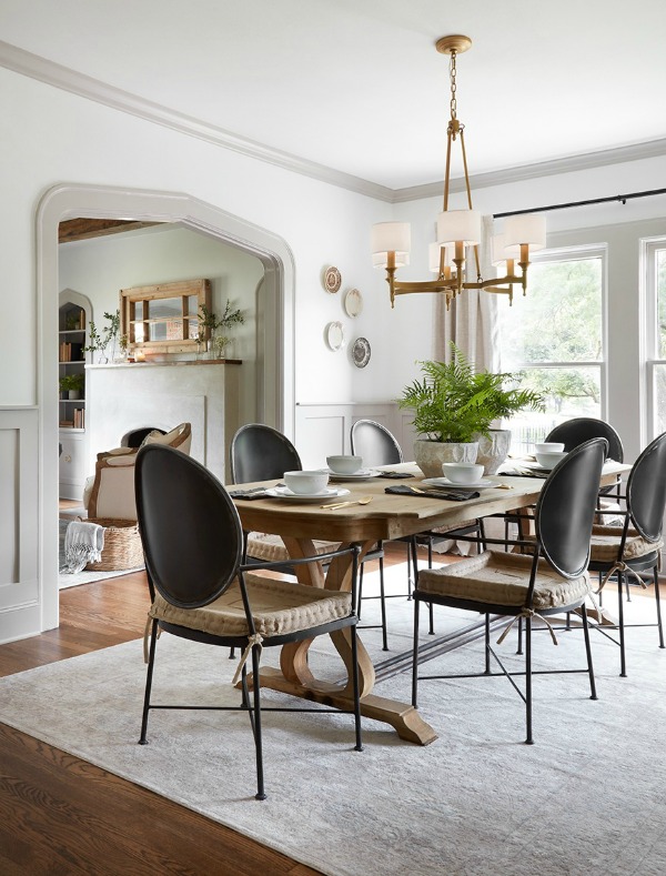 Dining room with modern Louis black chairs and farm table.  Come get inspired by Tranquil and Timeless Tudor Design Details From a Serene 1920s Texas Cottage renovated on HGTV's Fixer Upper by Chip and Joanna and known as the Scrivano House. #fixerupper #scrivano #cottagestyle #interiordesign #greytrim #serenedecor #diningroom