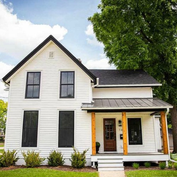 Charming 1900 renovated white urban farmhouse exterior in Beloit, WI with black windows, wood porch columns, and natural wood accents. #hellolovelystudio #urbanfarmhouse #houseexterior #modernfarmhouse #blackwindows