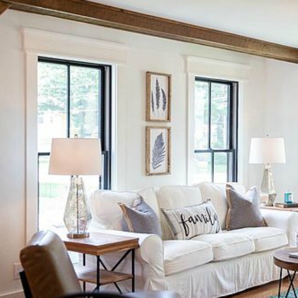 Urban farmhouse living room design with rustic beams, black windows, wood floors, and white sofa. #hellolovelystudio #urbanfarmhouse #interiordesign #modernfarmhouse #livingroom