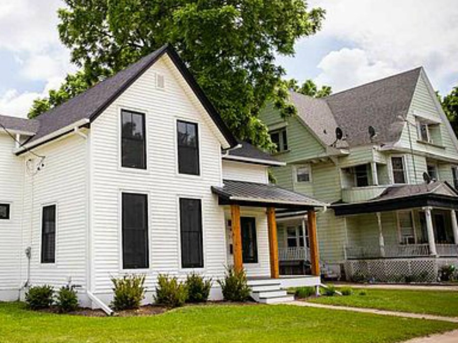 Charming 1900 renovated white urban farmhouse exterior in Beloit, WI with black windows, wood porch columns, and natural wood accents. #hellolovelystudio #urbanfarmhouse #houseexterior #modernfarmhouse #blackwindows