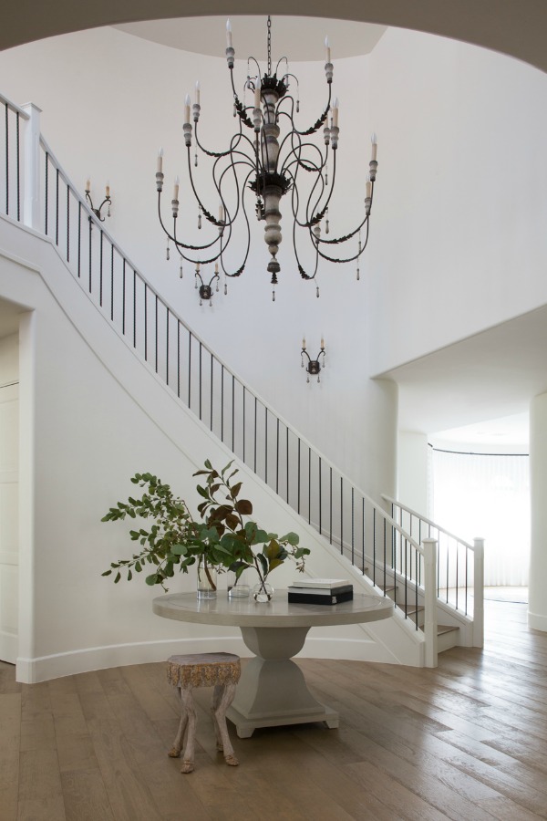 Entry with snowy white walls, French country chandelier and wrought iron staircase - Jaimee Rose Interiors.