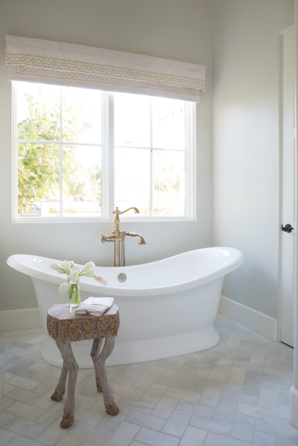 Beautiful white modern farmhouse bathroom with freestanding tub and herringbone tile floor - Jaimee Rose Interiors. #bathroomdesign #interiordesign