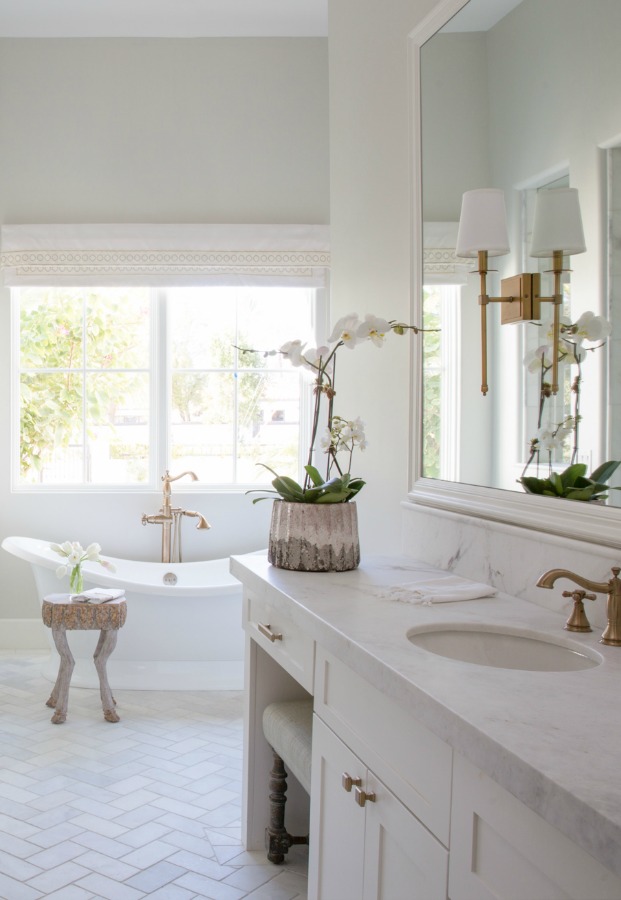 Beautiful white modern farmhouse bathroom with freestanding tub and herringbone tile floor - Jaimee Rose Interiors. #bathroomdesign #interiordesign