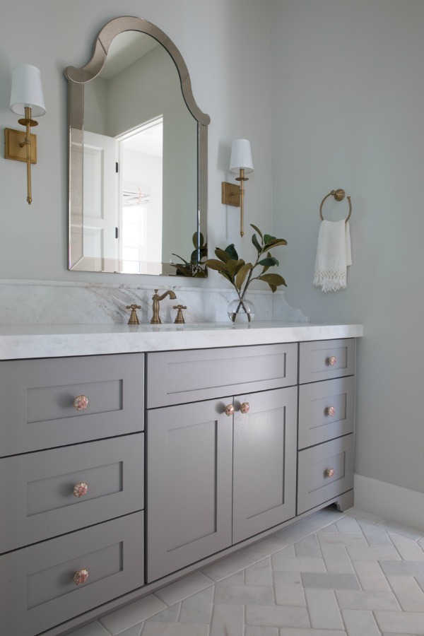 Beautiful modern farmhouse bathroom with grey vanity, brass fixtures and classic design by Jaimee Rose Interiors. #bathroomdesign #interiordesign