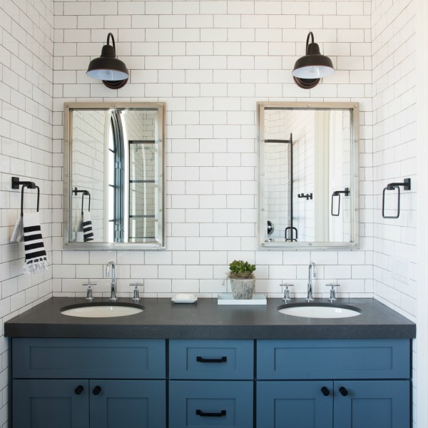 Modern farmhouse bathroom with blue double vanity, black counter, and white subway tile to celing on walls - Jaimee Rose Interiors.