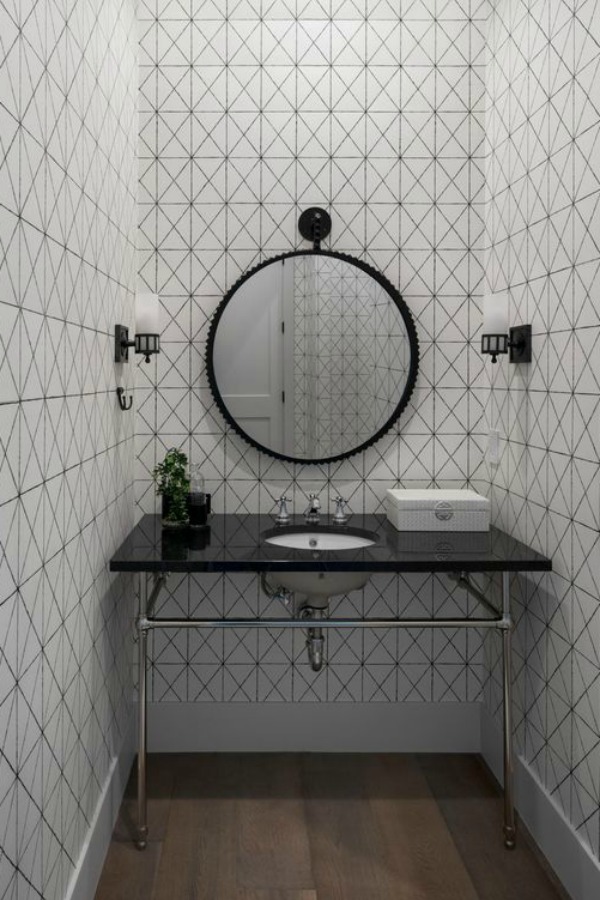 Modern bathroom design with black and white, console sink with black polished marble top, and round mirror.