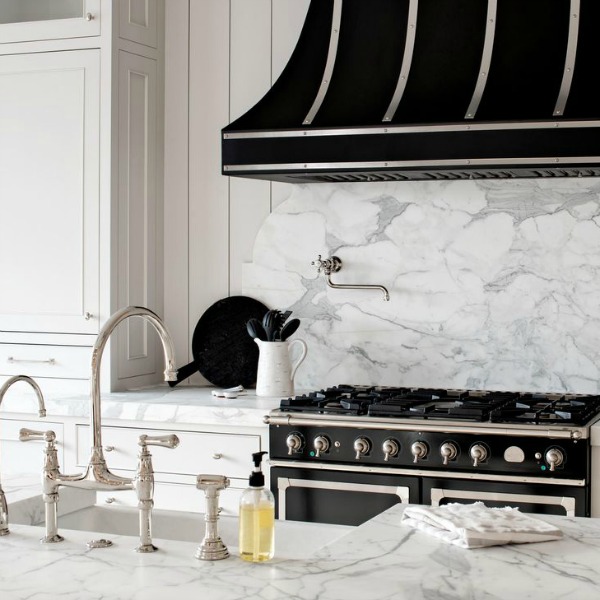 Black range hood over classic black range in white kitchen with marble backsplash - Jaimee Rose Interiors. #kitchendesign #blackandwhite #blackrange