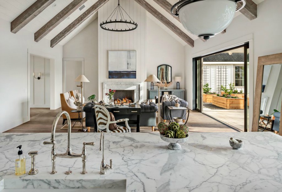 Modern farmhouse great room with open concept floorplan, rustic beams on ceiling, and accordion door open to patio - Jaimee Rose Interiors.