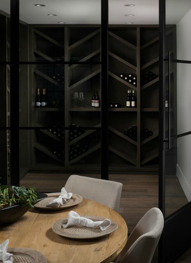 Wine cellar adjacent to a dining area with round table- interior design by Jaimee Rose Interiors.