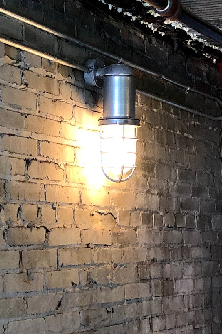 Industrial wall sconce bulkhead light shining on a rustic old brick wall in Franklin, TN - Hello Lovely Studio