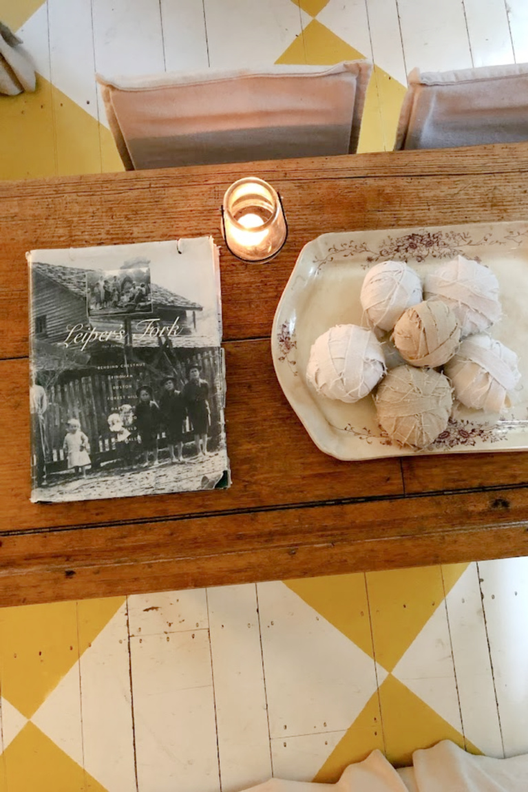 Brown transferware antique platter with balls of wrapped cloth and a candle upon a wood table - Hello Lovely Studio.