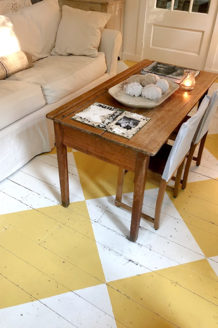 Lovely American country cottage living room in Leiper's Fork, TN, with yellow check wood floor, white decor and vintage, and art by Michele of Hello Lovely Studio.