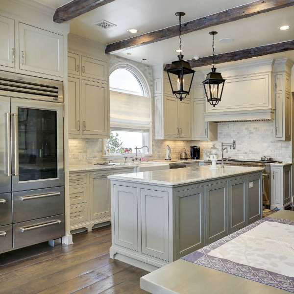 Sophisticated white and light grey French country kitchen with lantern pendants over island in a Houston home by Thomas O'Neill. #frenchcountry #kitchendesign #whitekitchen #traditionalkitchen