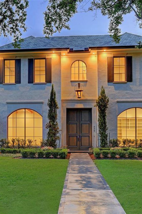 Exterior of a beautiful traditional Houston home with arched steel windows and lovely shutters.