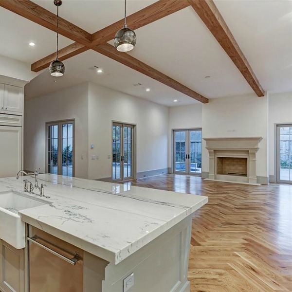 Elegant and sophisticated light grey and white kitchen with ceiling beams and herringbone wood floor. #kitchendesign #frenchcountry #customhomedesign #greycabinets