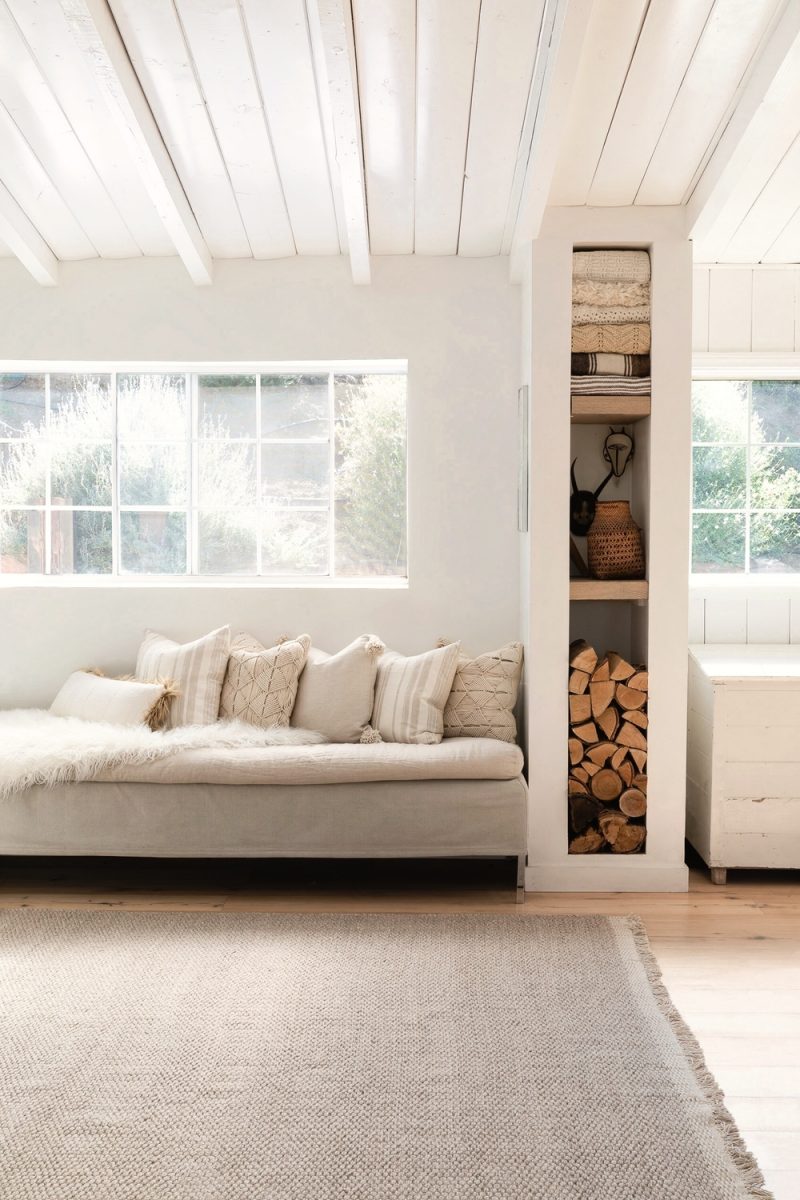 Linen daybed under sunny window and tower of shelves in a rustic zen modern farmhouse kitchen with white rafters and wood floors - Lulu & Georgia. Enjoy 7 Simple Ideas to Add Smiles to White Rooms + Funny Quotes!  #kitchendesign #rusticzen #modernfarmhouse #windowseat