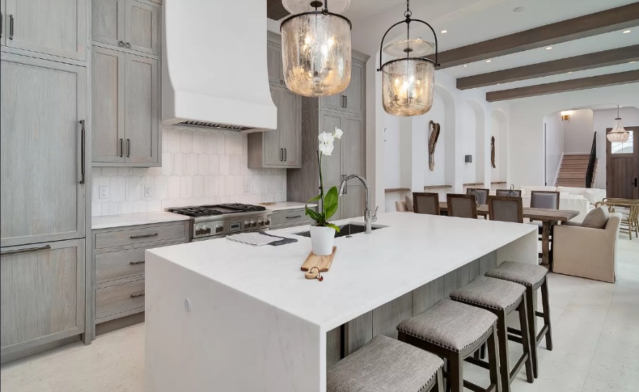 Understated, muted neutrals in a luxurious kitchen and breakfast room of a coastal home (Alys Beach) by Domin Bock. #kitchendesign #warmminimal #luxuriouskitchen #greycabinets #customkitchen