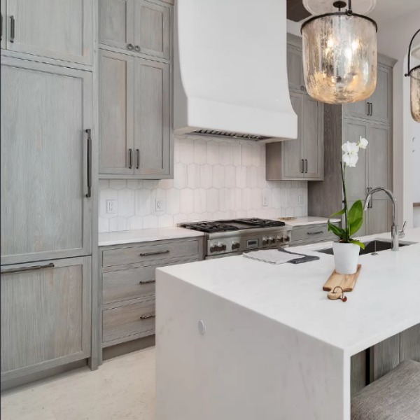 Understated, muted neutrals in a luxurious kitchen and breakfast room of a coastal home (Alys Beach) by Domin Bock. #kitchendesign #warmminimal #luxuriouskitchen #greycabinets #customkitchen