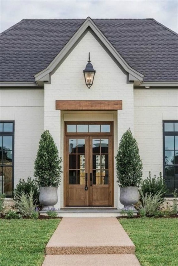 Beautiful white painted brick house exterior with natural wood double door entrance - AACMM. #housedesign #whitebrick #curbappeal