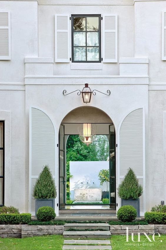 Magnificent white home exterior with arched shutters and magnificent lantern - Luxe Home. #houseexterior #housedesign #shutters