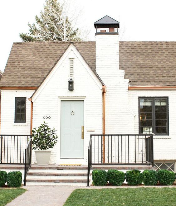 Beautiful white Tudor home exterior in Denver by Studio McGee with brick painted Benjamin Moore China White and front door Greyhound. #whitebrick #studiomcgee #bricktudor #houseexterior #benjaminmoorechinawhite #benjaminmooregreyhound #paintcolors