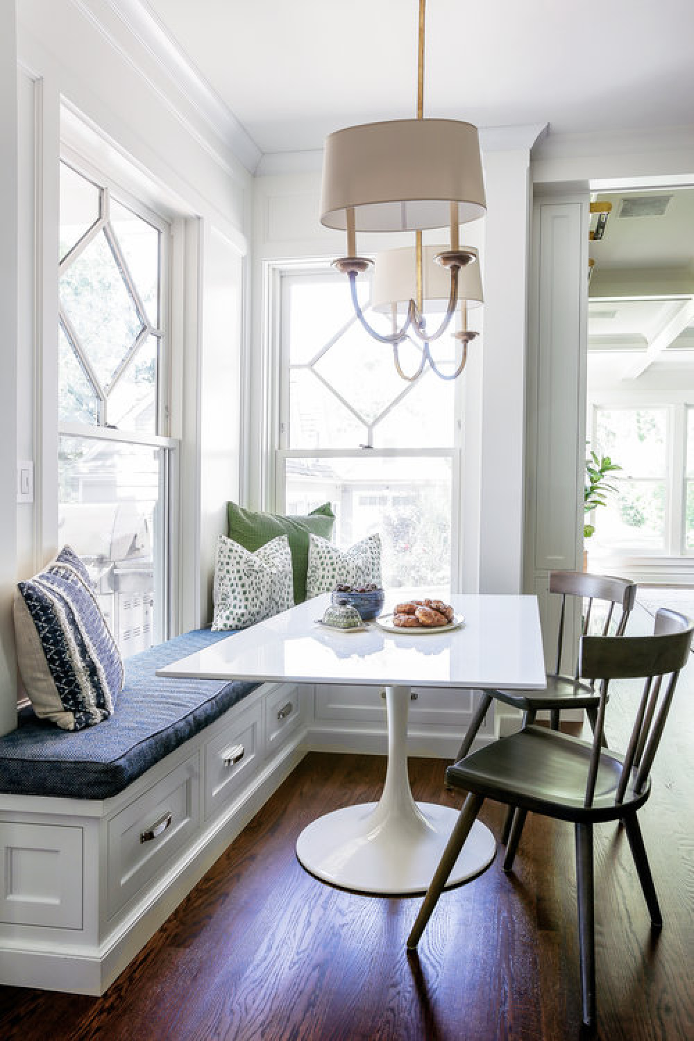 Classic style in a breakfast nook of a traditional white kitchen with blue accents, custom millwork, and built-in window seat - Edward Deegan Architects.