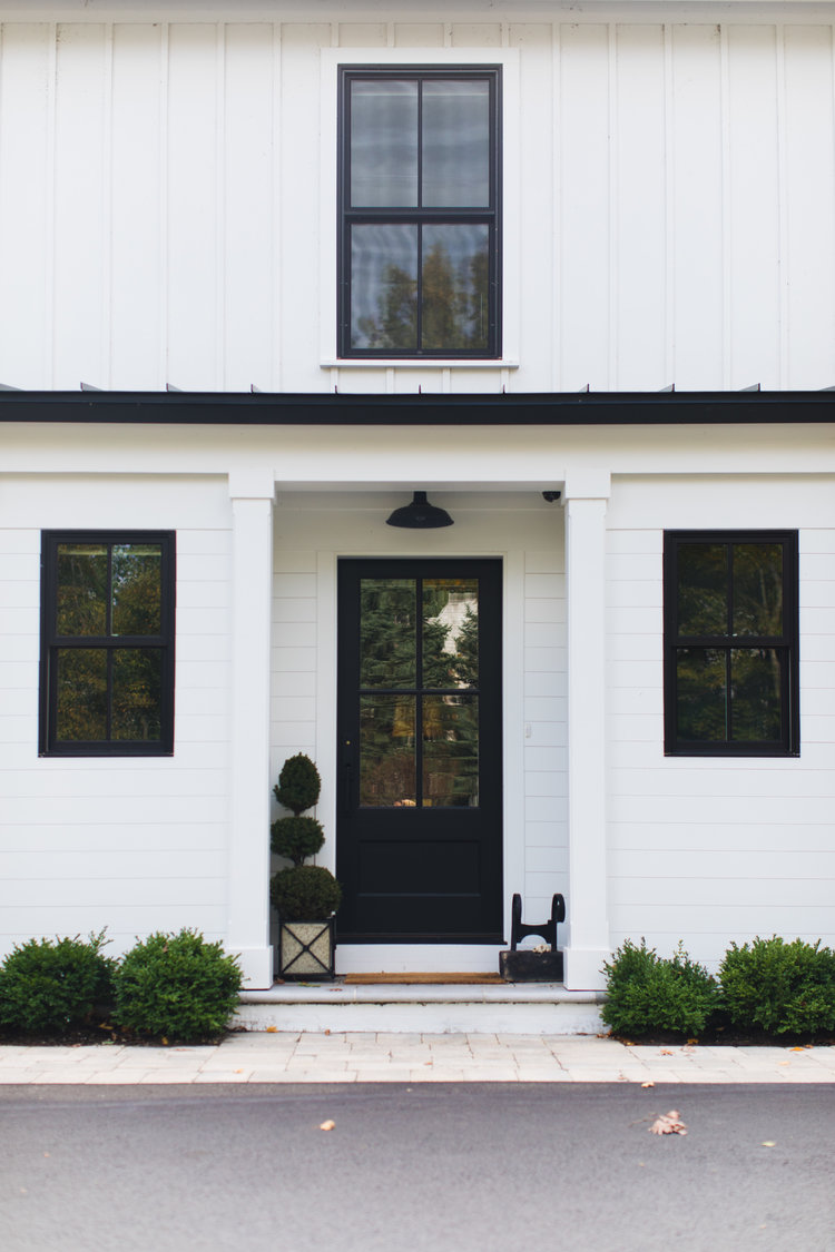 White and black modern farmhouse exterior with black front door and black windows - Edward Deegan Architects. #modernfarmhouse #blackandwhite #houseexteriors #housedesign