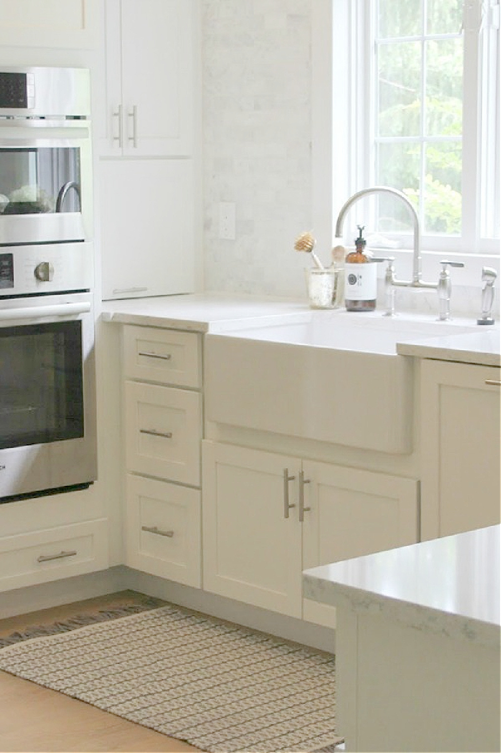White Shaker classic kitchen with fireclay farm sink, Bosch double ovens, Viatera Minuet quartz counters and polished Venatino marble subway backsplash tile - Hello Lovely Studio.