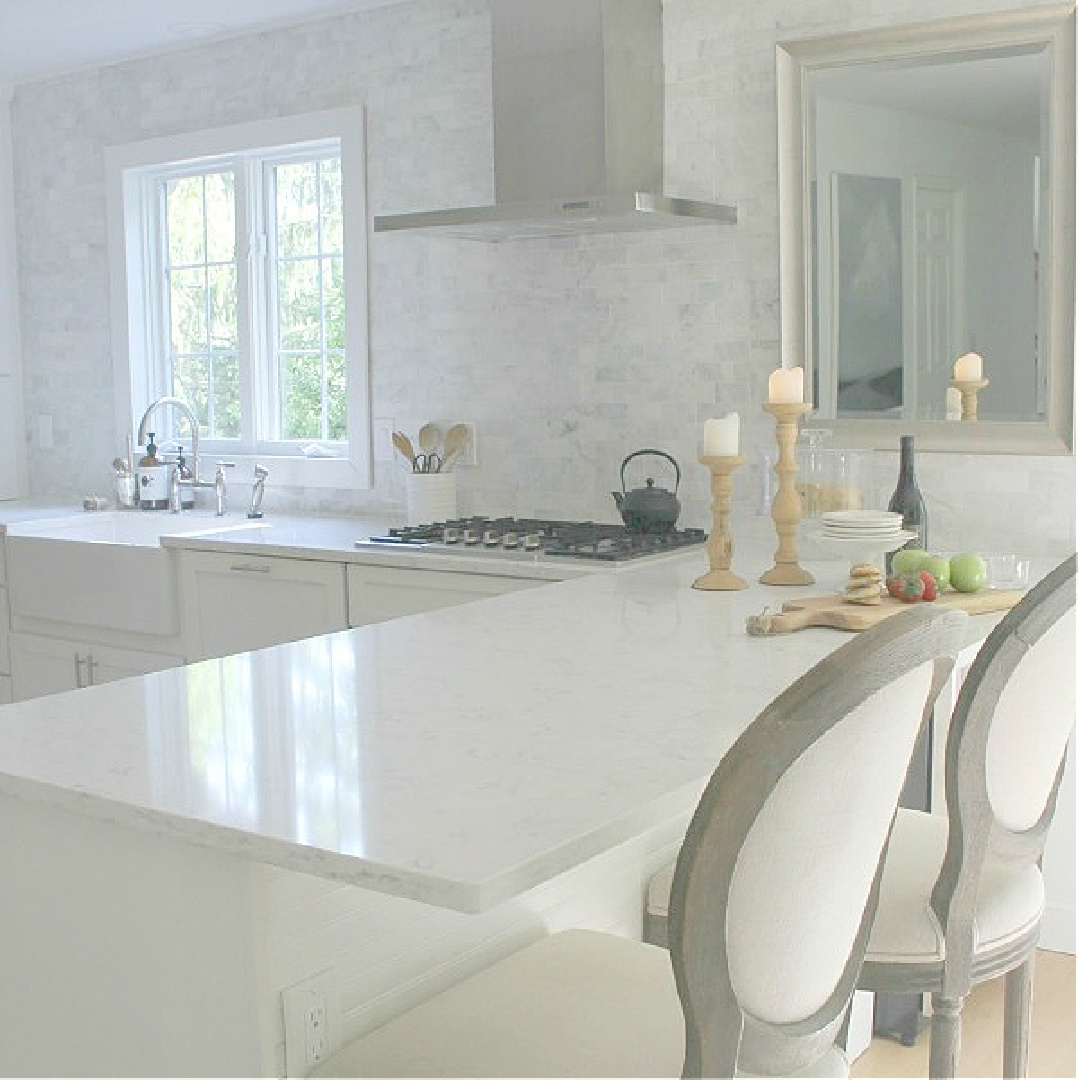 Modern French white kitchen with Viatera Minuet countertops, stainless Italian range hood, and farm sink - Hello Lovely Studio.