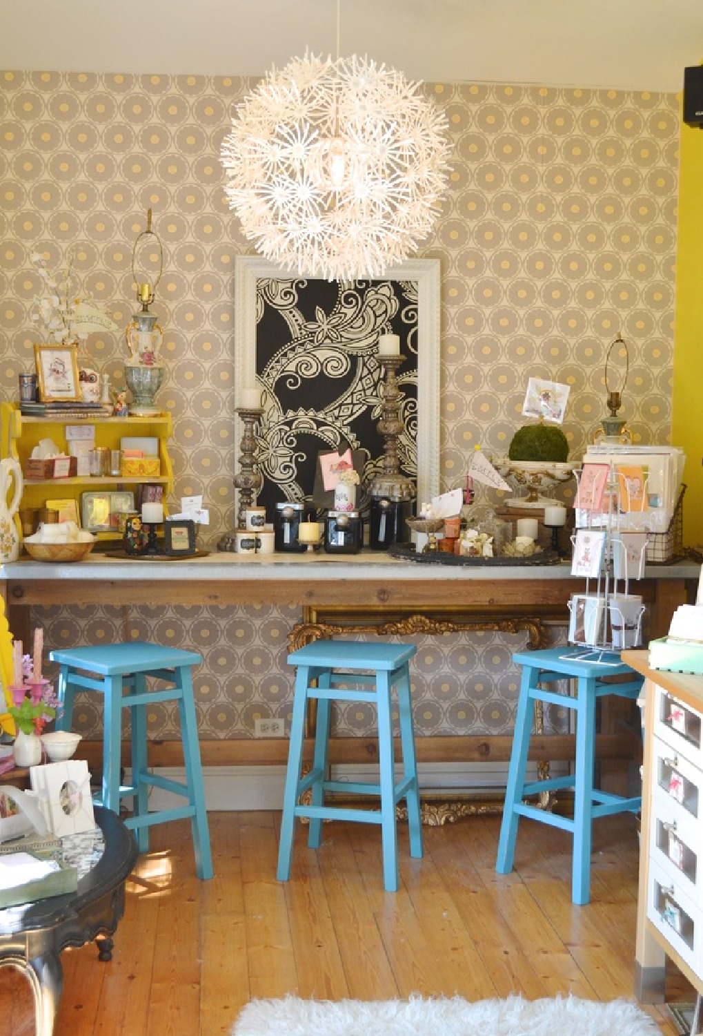 Whimsical bar with cheerful blue stools in a boho fun art studio with yellow accents - Jenny Sweeney.