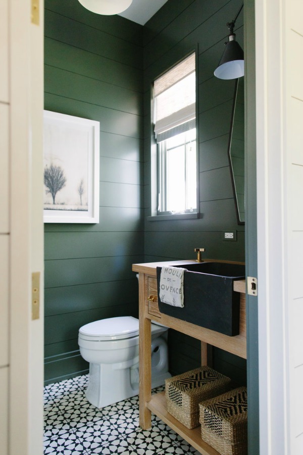 A moody deep dark green paint covers shiplap clad walls in a powder bath with farm sink by Kate Marker in Barrington, IL. Come enjoy encouraging love quotes and timeless decor inspiration! #interiordesign #bathroomdesign #shiplap #greenpaint #darkgreen