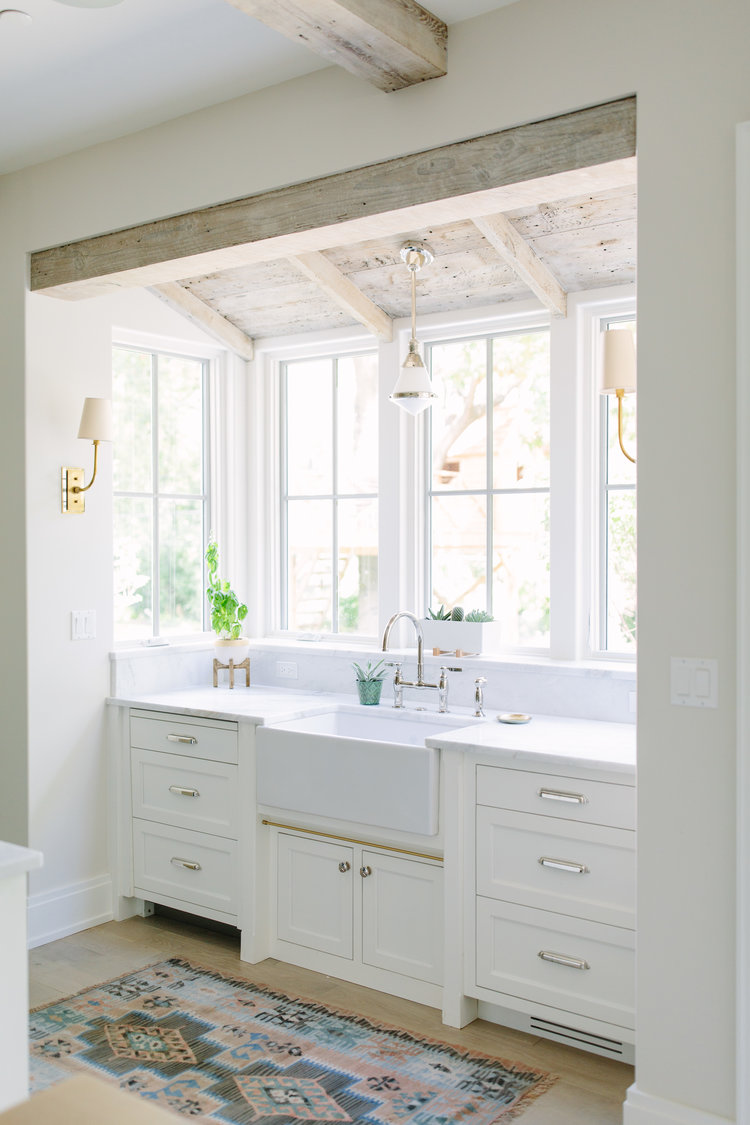 Charming modern farmhouse sink bay in a kitchen with rustic wood ceiling and design by Kate Marker in Barrington, IL. #modernfarmhousekitchen #farmsink #serenedecor