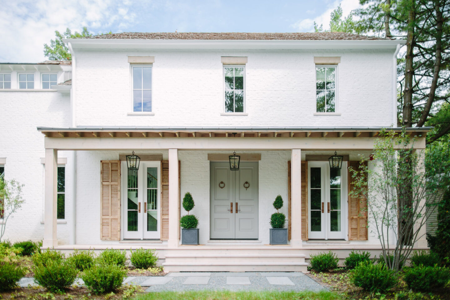 Charming and romantic modern farmhouse exterior facade with lime washed brick, rustic natural wood shutters, and light grey front door. Interiors by Kate Marker in Barrington, IL. #houseexterior #housedesign #modernfarmhouse #whitebrick #curbappeal #greyfrontdoor