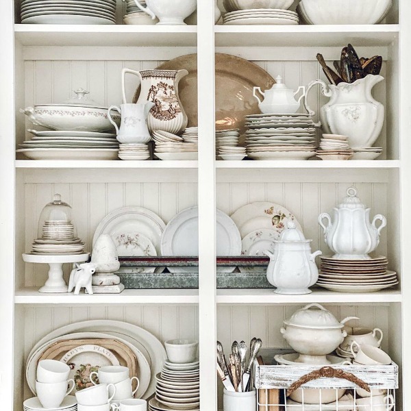 Rustic white beadboard backed shelves in a country cabinet filled with white vintage treasures - Le Cultivateur. #whitecountrydecor #countrycabinet #beadboard #toneontone #vintagestyle