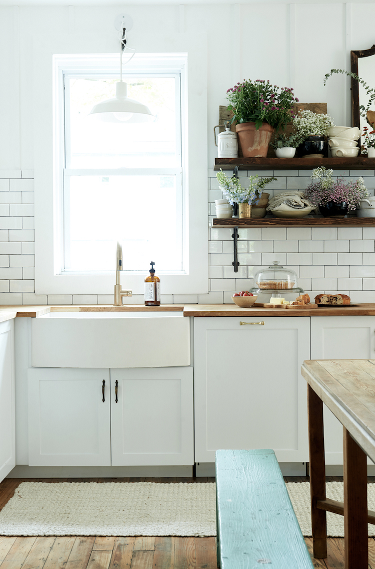 Farm sink, subway tile backsplash, and open shelving in a modern farmhouse kitchen by Leanne Ford. #restoredbythefords #leanneford #modernfarmhousekitchen #farmsink #modernrustic #interiordesign