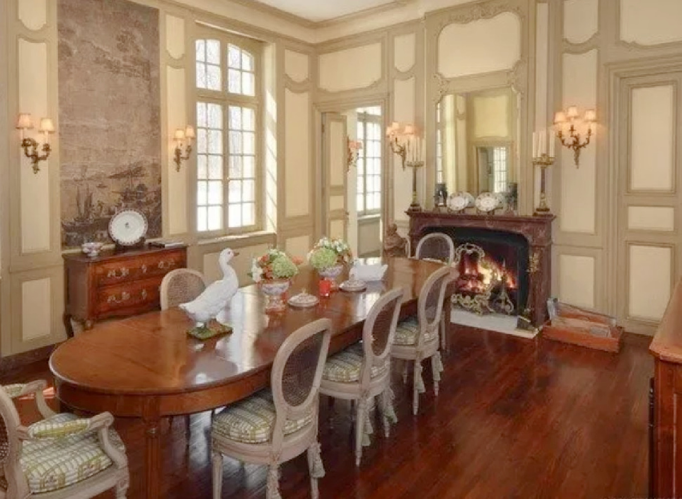 Dining room with paneling in a French country interior with fireplace. David Adler La Lanterne Mansion is a 1922 historic home in Lake Bluff with French inspired architecture and interiors.