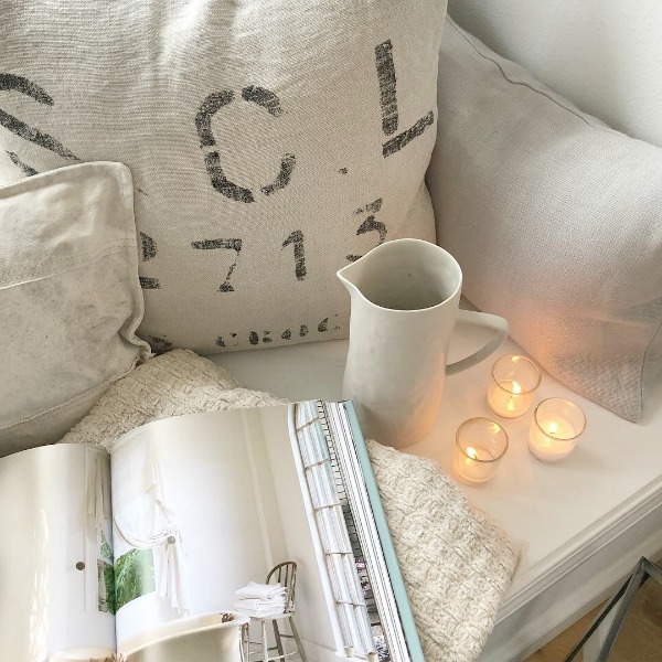 Tone on tone palette at cozy window seat with pillows and candlelight - Hello Lovely Studio. #windowseat #allwhitedecor #scandinavianstyle #interiordesign