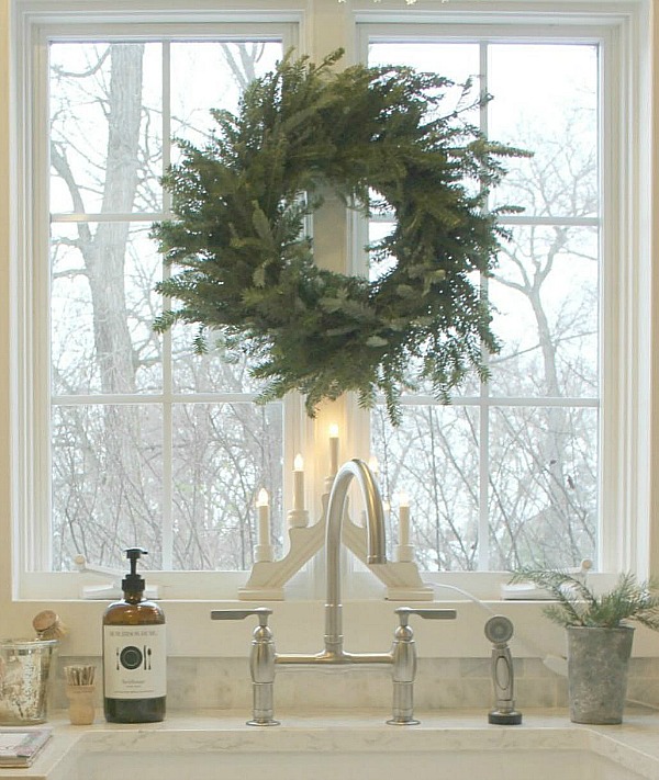 Frasier fir wreath at kitchen sink window in Hello Lovely Studio's French Nordic kitchen with farm sink. Find a Soft, Ethereal European Country Kitchen Mood to Inspire Now!