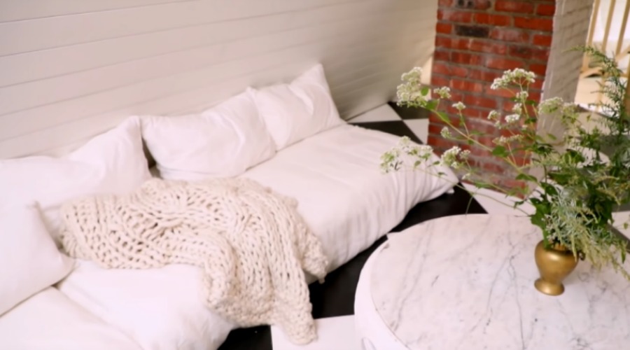 Black and white checkered painted wood floor in an attic with paneled walls and white bedding with cable knit throws. Design by Leanne Ford. #leanneford #whitedecor #blackandwhite #interiordesign