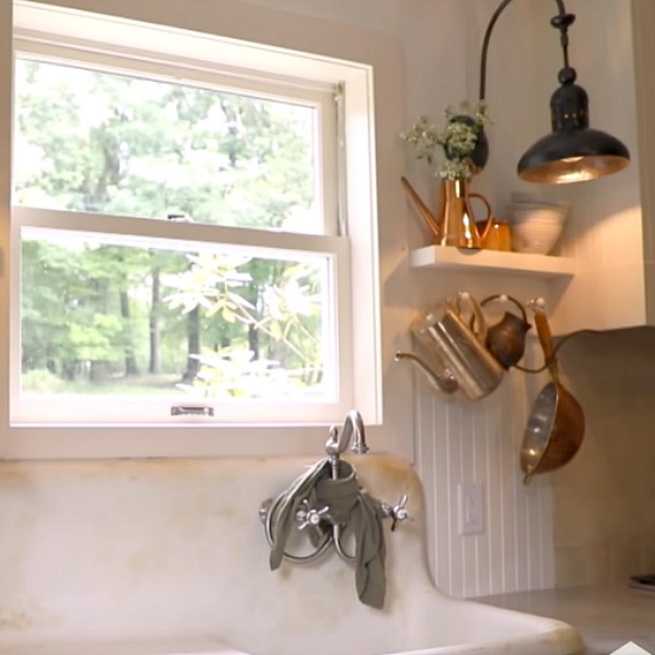 Beadboard on walls, white Shaker cabinets, and a vintage farm sink play starring roles in a cottage kitchen with rustic luxe style from Leanne Ford. #rusticdecor #kitchendesign #leanneford