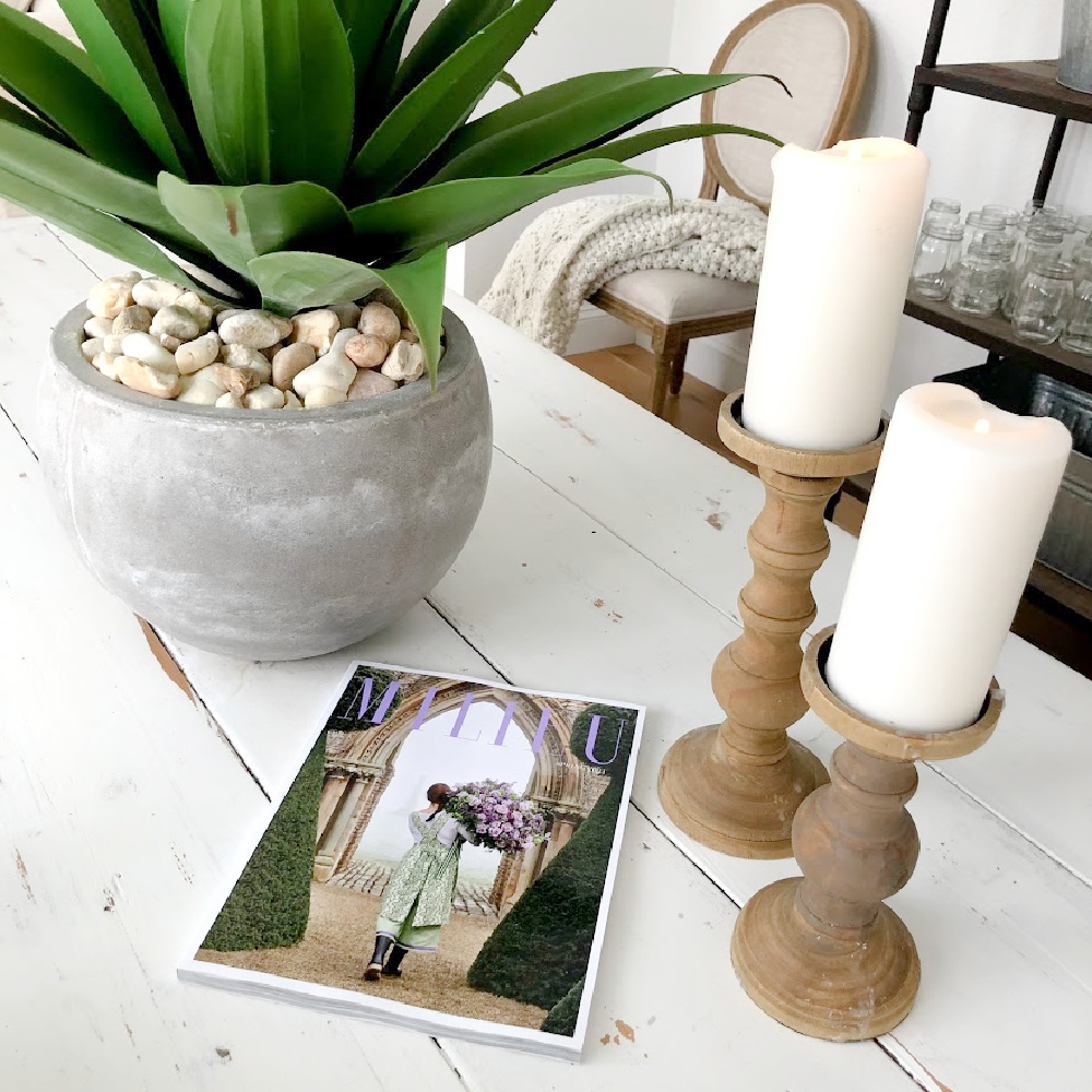 Serene white modern French dining room with farm table, rustic wood candleholders, and succulent in rustic pot - Hello Lovely Studio. #allwhitedecor #modernfrench #diningroom