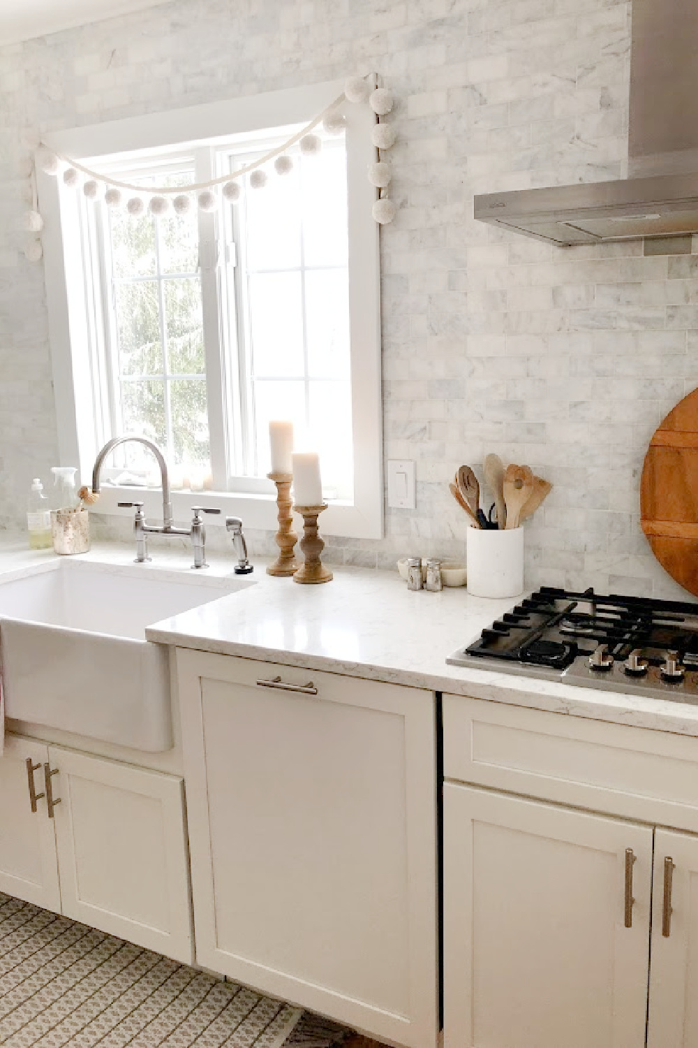 Serene European country farmhouse kitchen with farm sink, Viatera Minuet counters, and marble subway tile backsplash - Hello Lovely Studio.