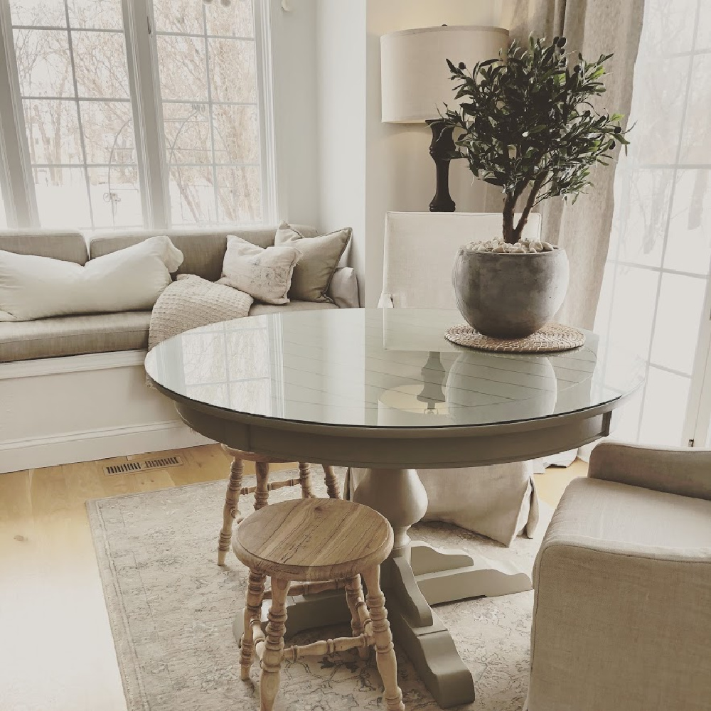 Serene neutral European country cottage breakfast nook with dining table, Belgian linen slipcovered chairs and window seat - Hello Lovely Studio. #europeancountrycottage #breakfastnook #windowseat #belgianlinen