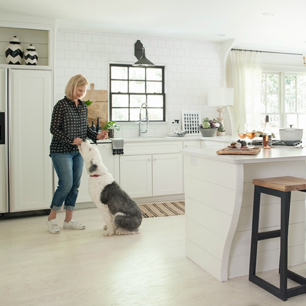 Sherry Hart and her Old English Sheepdog in her beautiful white Atlanta kitchen with shiplap and architectural interest. #whitekitchen #interiordesign #kitchendesign