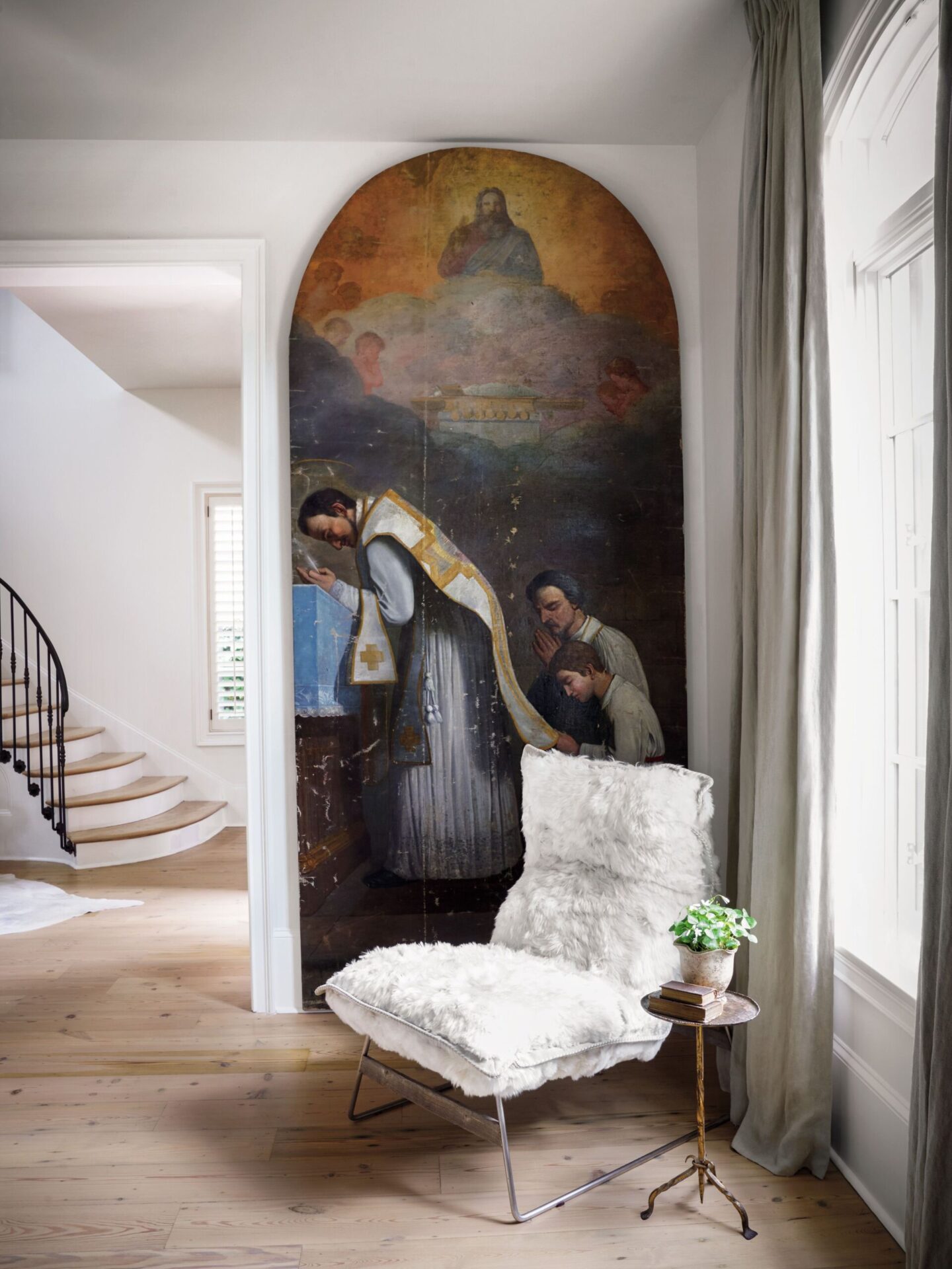 Two massive 19th century ecclesiastical paintings by Victor Mazies mix with a modern alpaca-covered chair in a living room designed by Tara Shaw. #oldworldstyle #tarashaw #religiousart #europeanantiques #interiordesign #rusticelegance