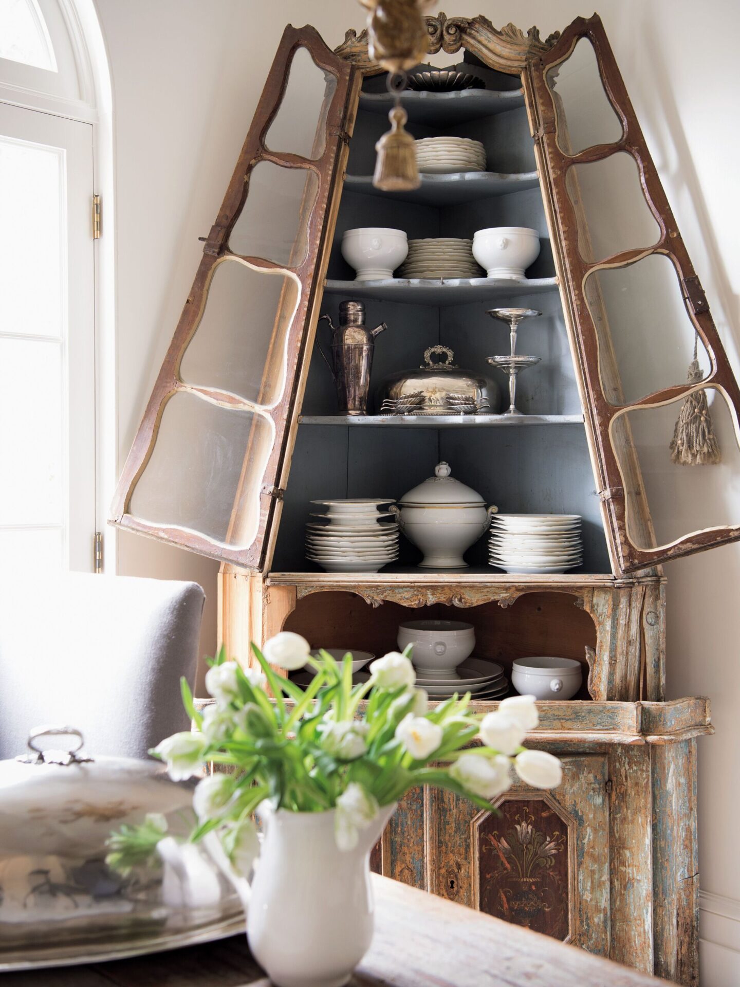 Exquisite with original paint antique Venetian corner cabinet stores white china and silver. Keys with burlap tassels serve as handles to pull open doors and complement worn finishes. #tarashaw #venetian #europeanantiques #antiques #cornercabinet #interiordesign #oldworldstyle #timelessdesign