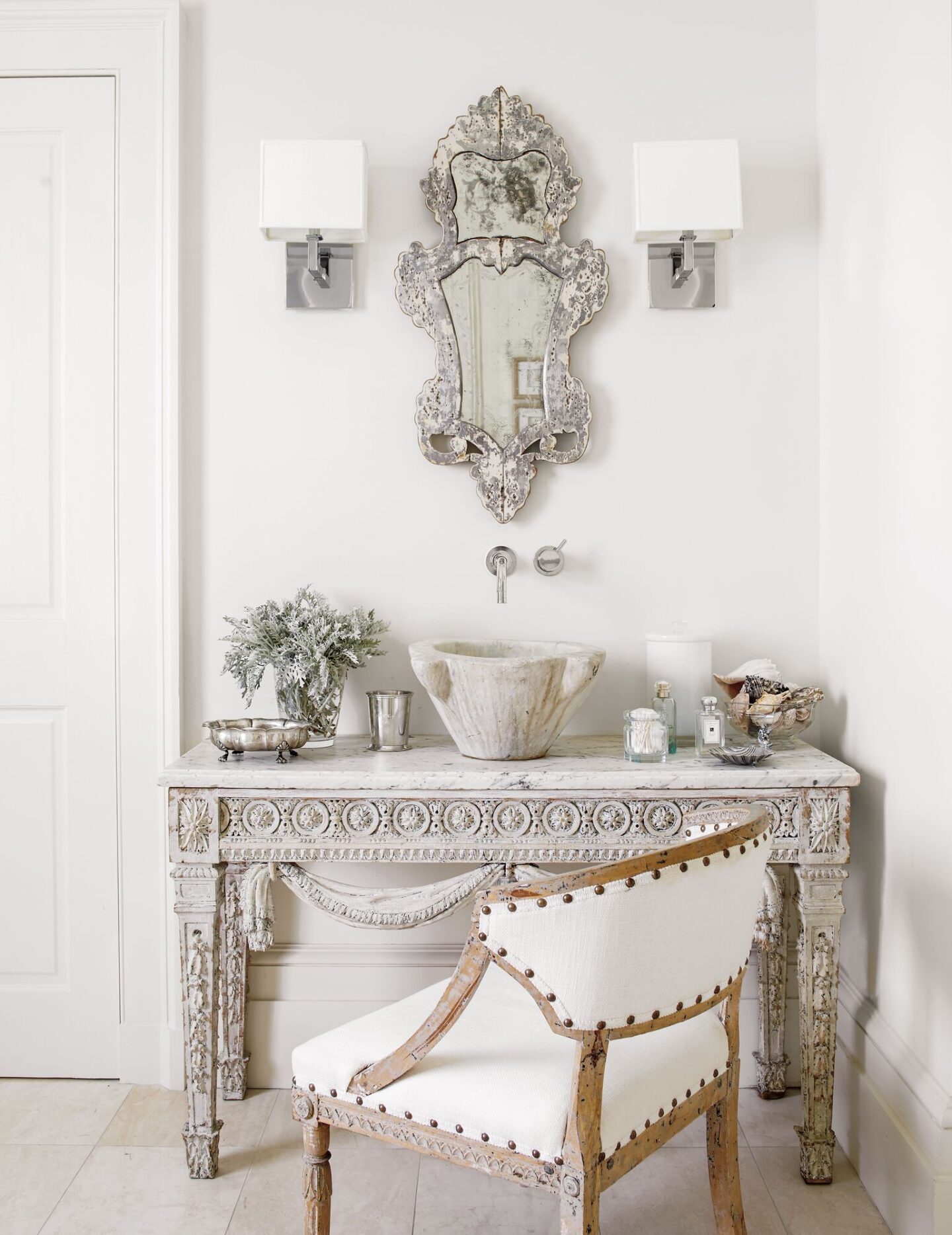 Elegant and luxe, this master bathroom vanity was created from an 18th century French painted console. An 18th century mortar became a sink which Shaw paired with an 18th century Swedish barrel-back chair. #tarashaw #oldworldstyle #interiordesign #antiques #swedishantiques #frenchantiques #stonesink