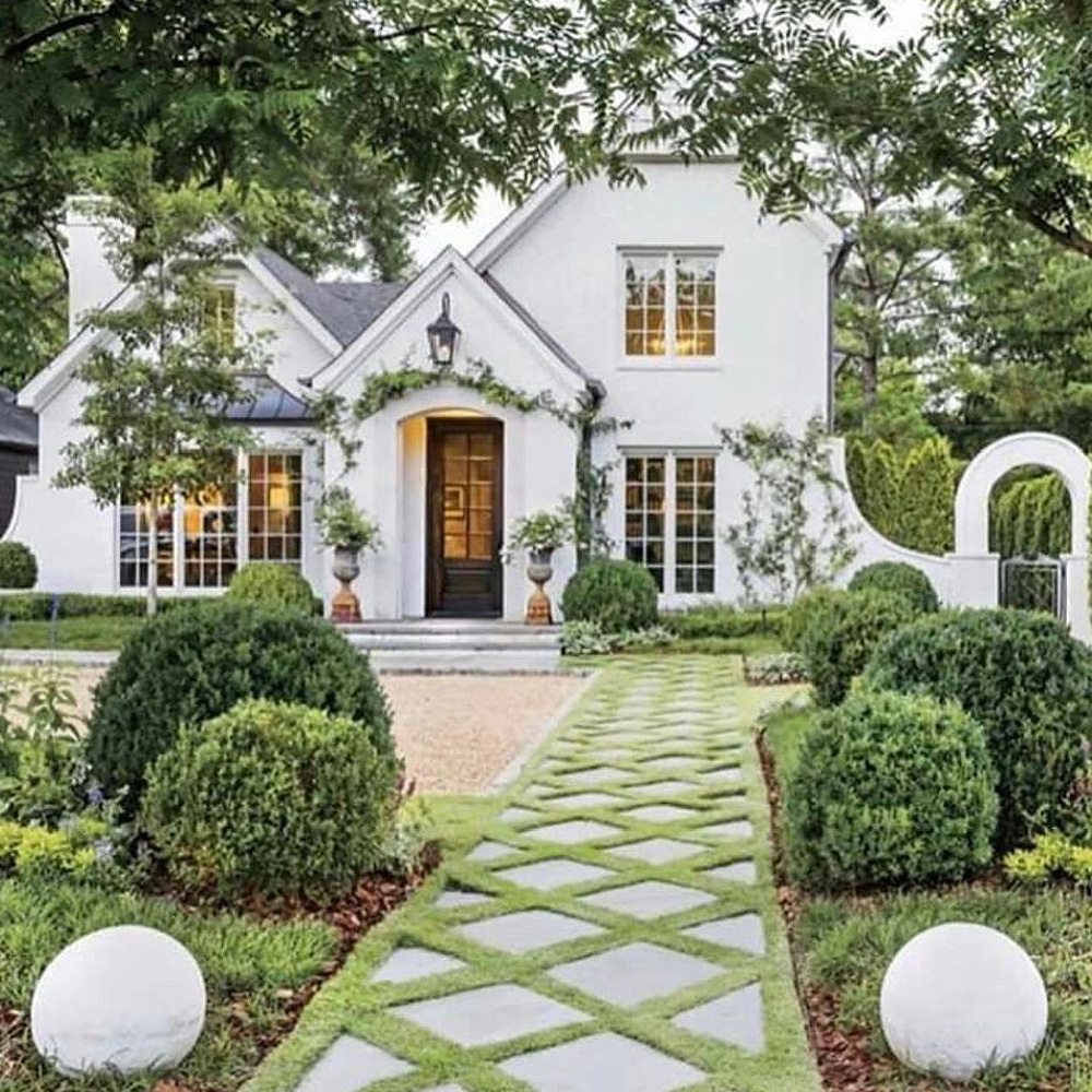 Exquisite lattice patterned landscaped walkway to charming white Tudor home - TMD Landscape Design. Charming inspiration if you love white painted house exteriors! #whitehouses #housedesign #exteriors #Tudor #landscapedesign #curbappeal